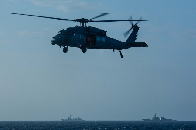 With a People's Liberation Army (Navy) vessel operating nearby [ed. note: a Type 815 electronic surveillance ship], an MH-60S Seahawk assigned to Helicopter Sea Combat Squadron (HSC) 14, currently embarked aboard USS John C. Stennis (CVN 74), conducts routine flight operations during a replenishment at sea in the South China Sea. (U.S. Navy/MC3 Kenneth Rodriguez Santiago) 